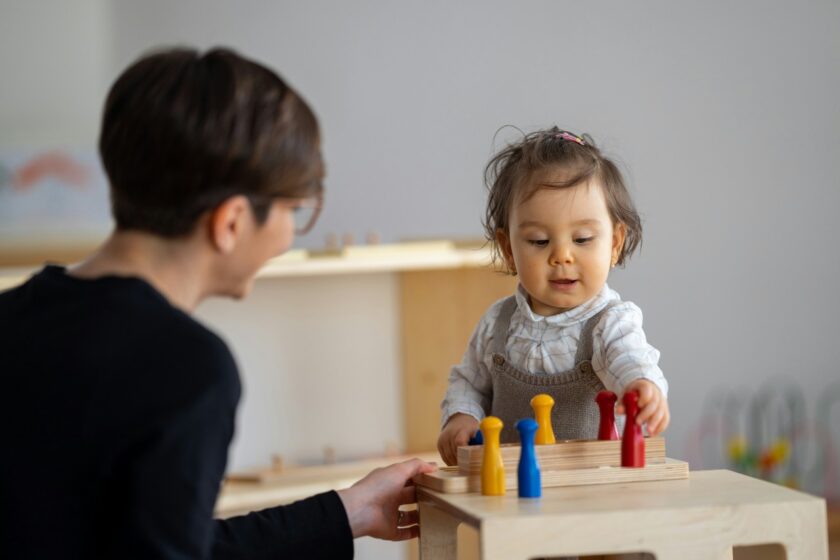 Teacher encouraging child learning with toys.