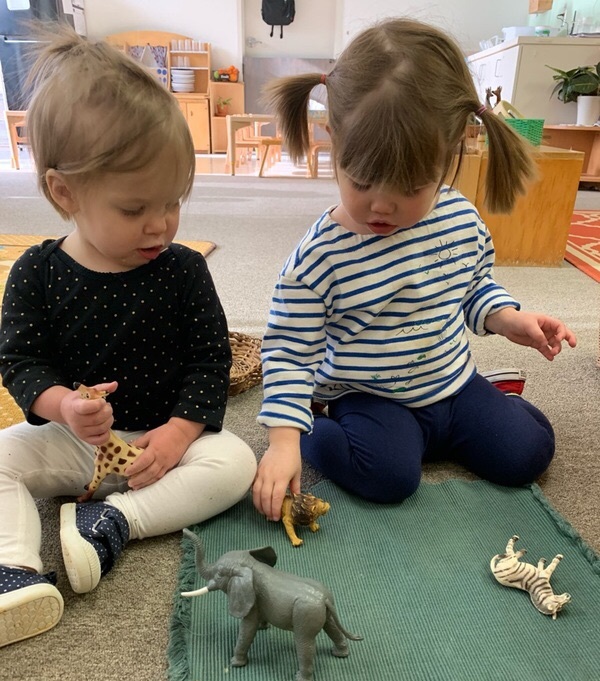 Little kids playing with toy animals.